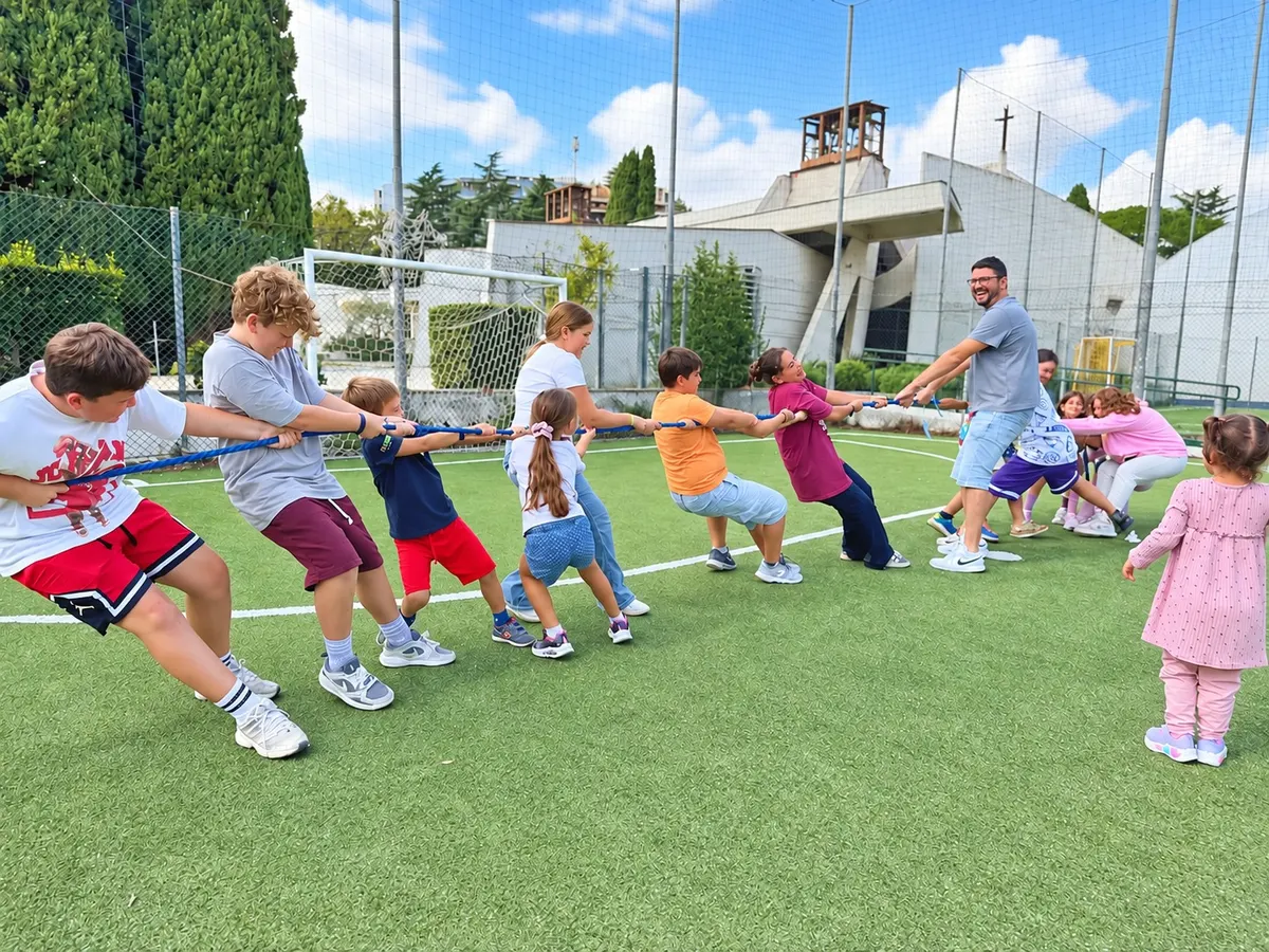 Bambini, ragazzi e animatori giocano al tiro alla fune sul campo sportivo dell’oratorio della parrocchia Santa Maria del Carmelo a Mostacciano, Roma