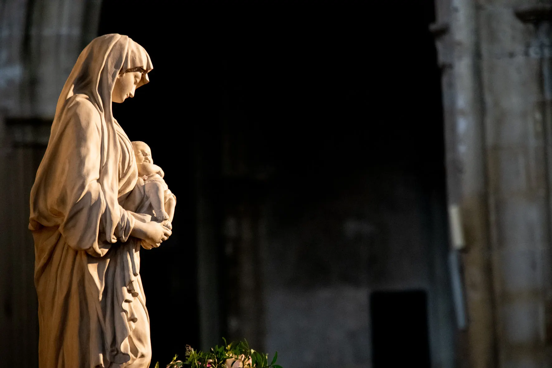 Statua della Madonna con il Bambino nella penombra della chiesa