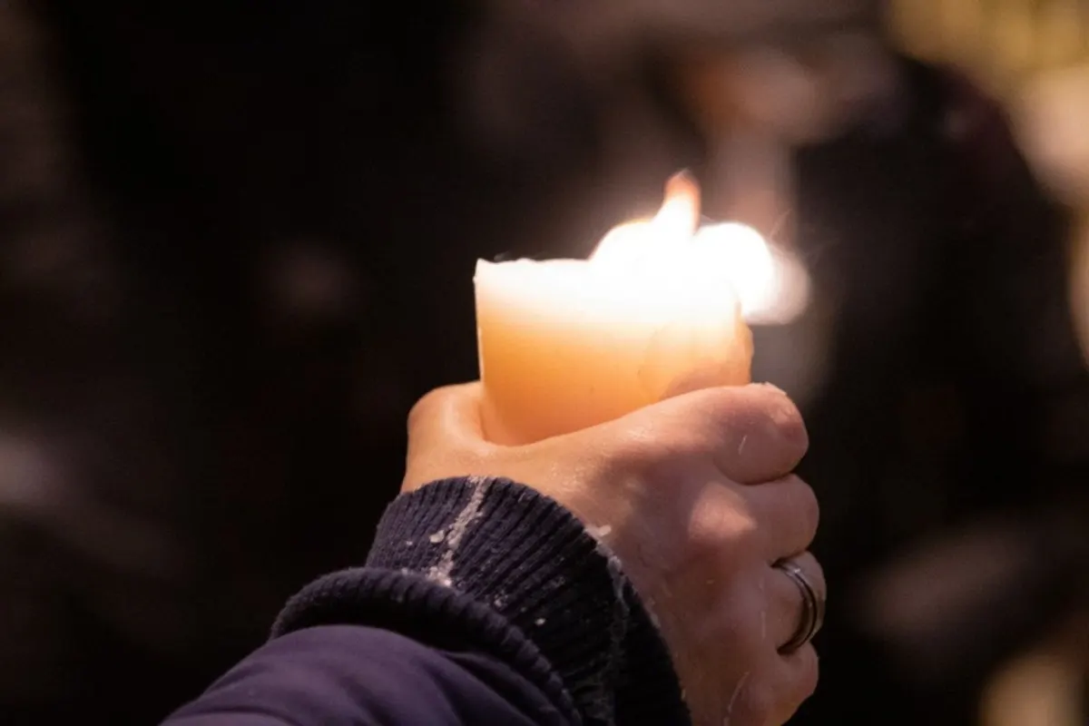 Una mano regge una candela accesa nel buio, segno di preghiera per la pace